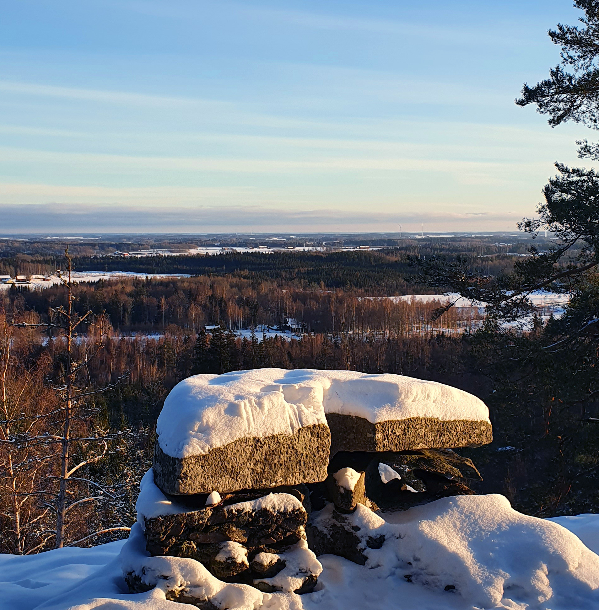 Ett stentorn på en utsiktplats där man ser ut över vidsträckt skog i snö.